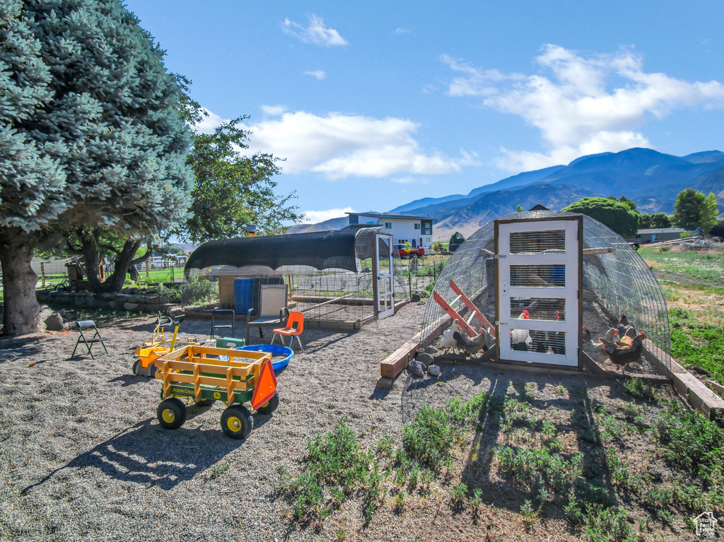View of play area featuring a mountain view, an outbuilding, and exterior structure