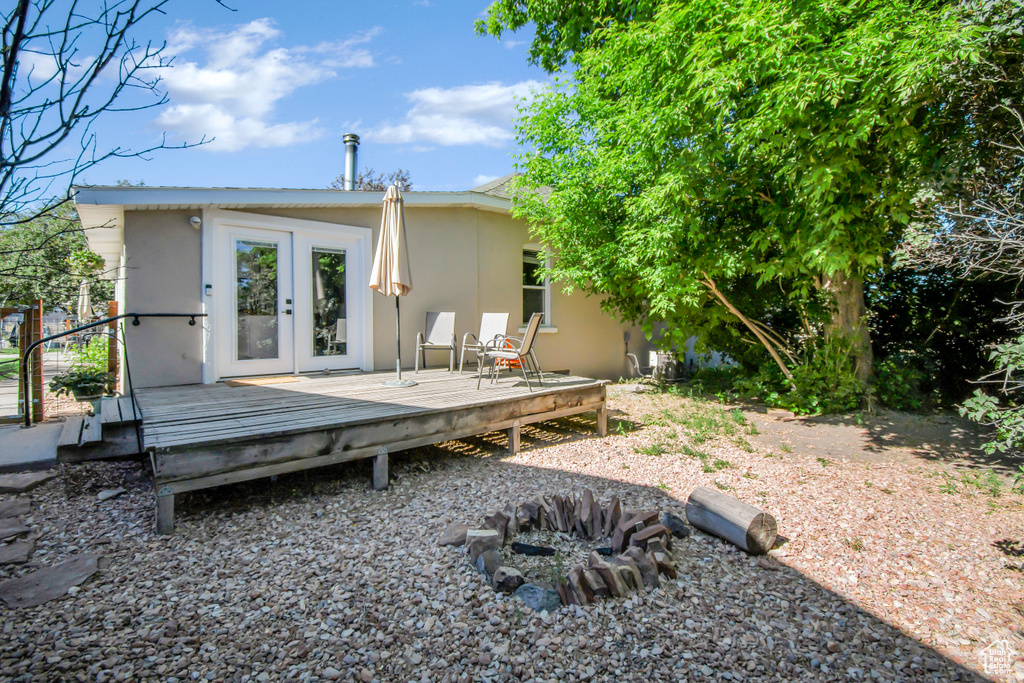 Back of property featuring a wooden deck, stucco siding, and french doors