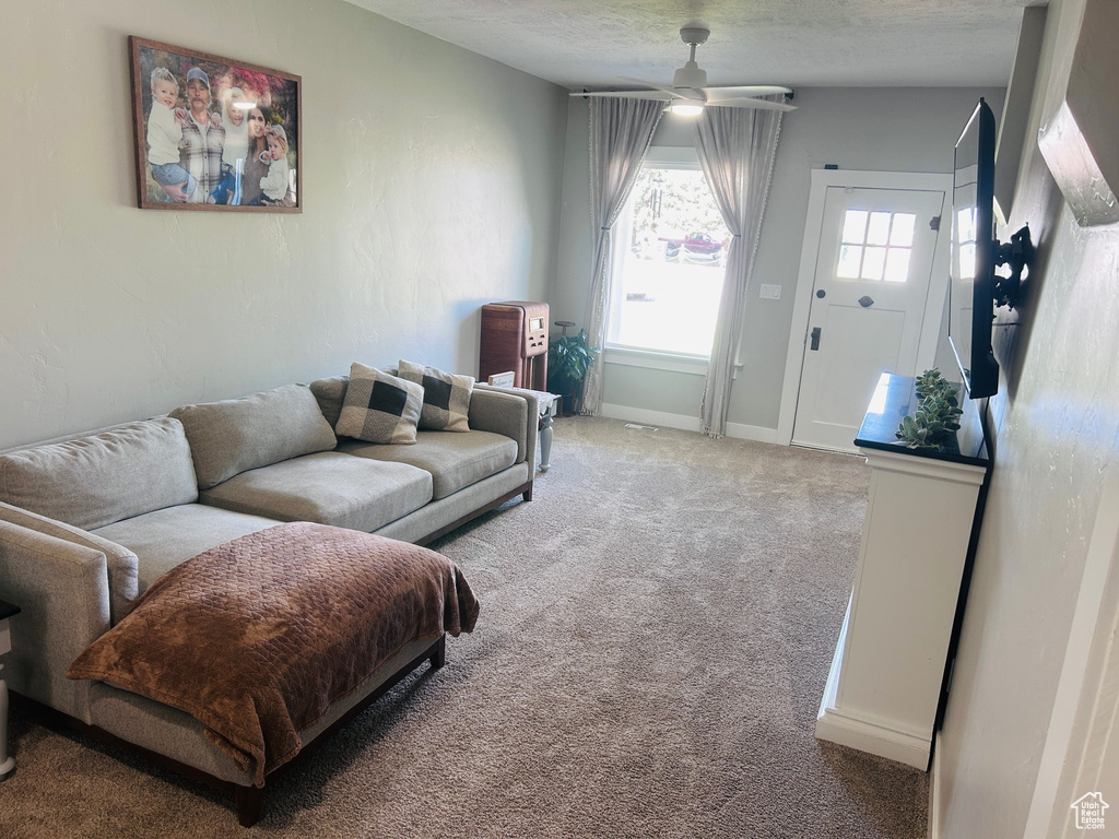 Carpeted living room with a ceiling fan and baseboards