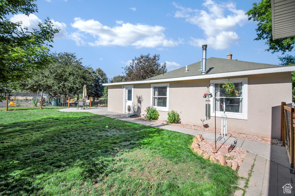 Rear view of property with stucco siding, a patio, a chimney, and roof with shingles