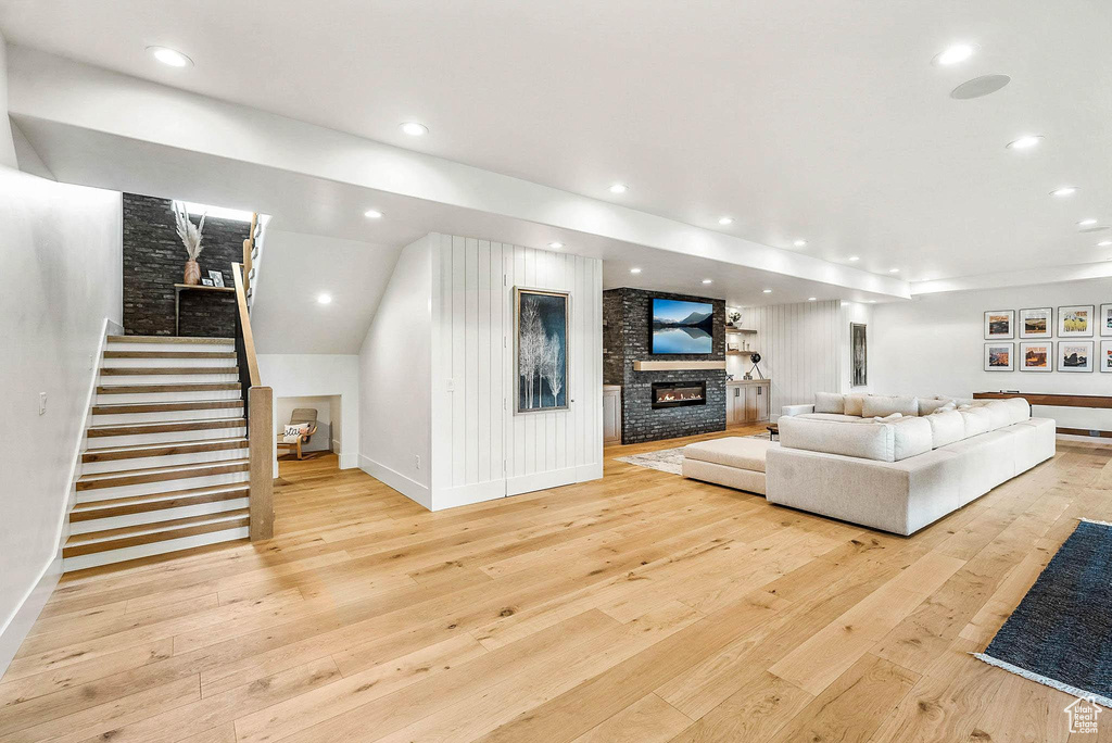 Living room featuring hardwood / wood-style flooring, stairway, a large fireplace, and recessed lighting