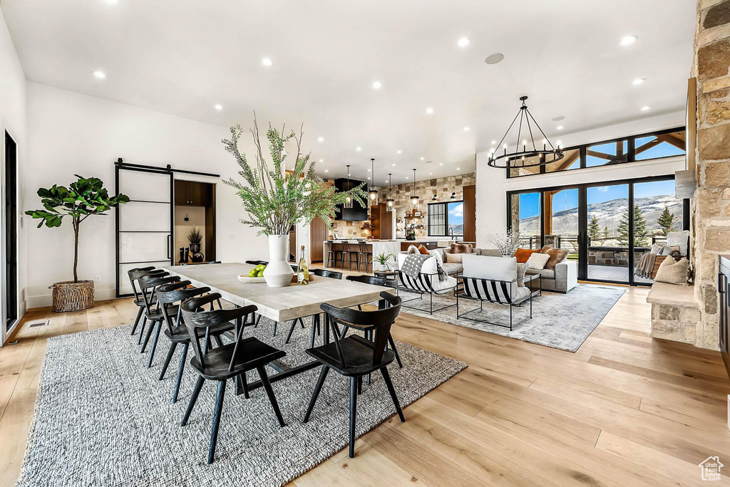 Dining room with a barn door, light wood finished floors, recessed lighting, and a chandelier