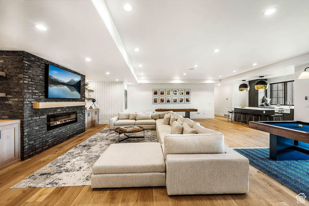Living room with light wood finished floors, a glass covered fireplace, pool table, and recessed lighting