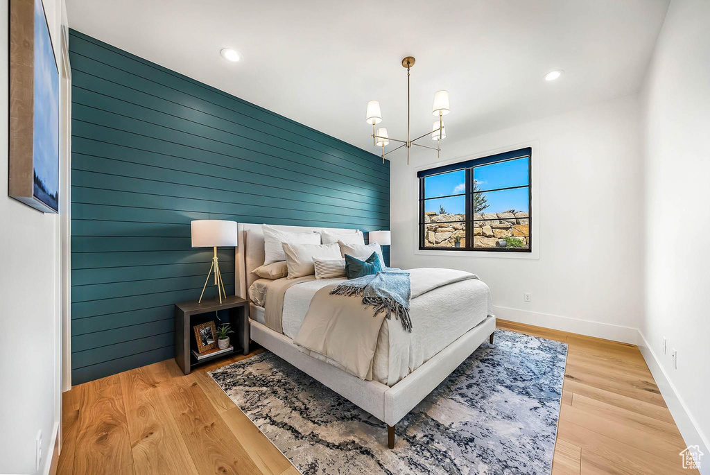 Bedroom with a chandelier, recessed lighting, wood finished floors, and wood walls