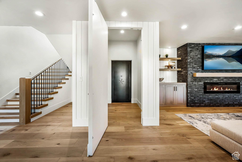 Living room with stairs, wood finished floors, a glass covered fireplace, and recessed lighting