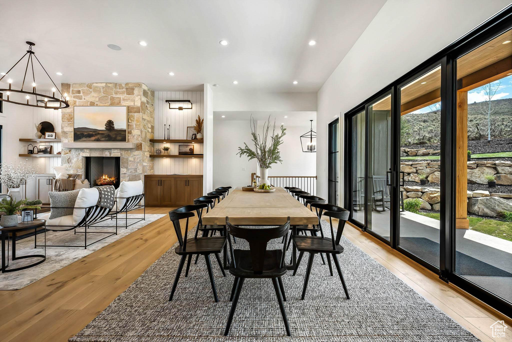 Dining space with a chandelier, light wood-type flooring, a fireplace, and recessed lighting