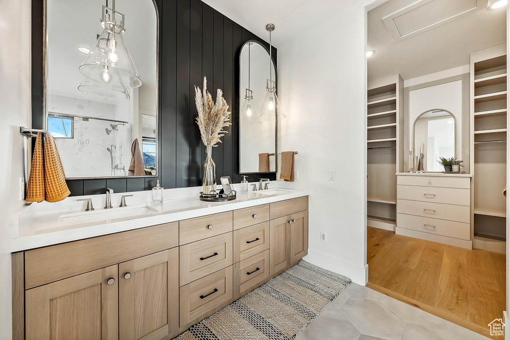 Full bath featuring double vanity, a walk in closet, a stall shower, and tile patterned floors
