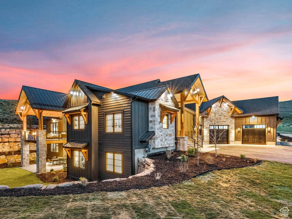 Property exterior at dusk featuring board and batten siding, a standing seam roof, a yard, driveway, and a metal roof