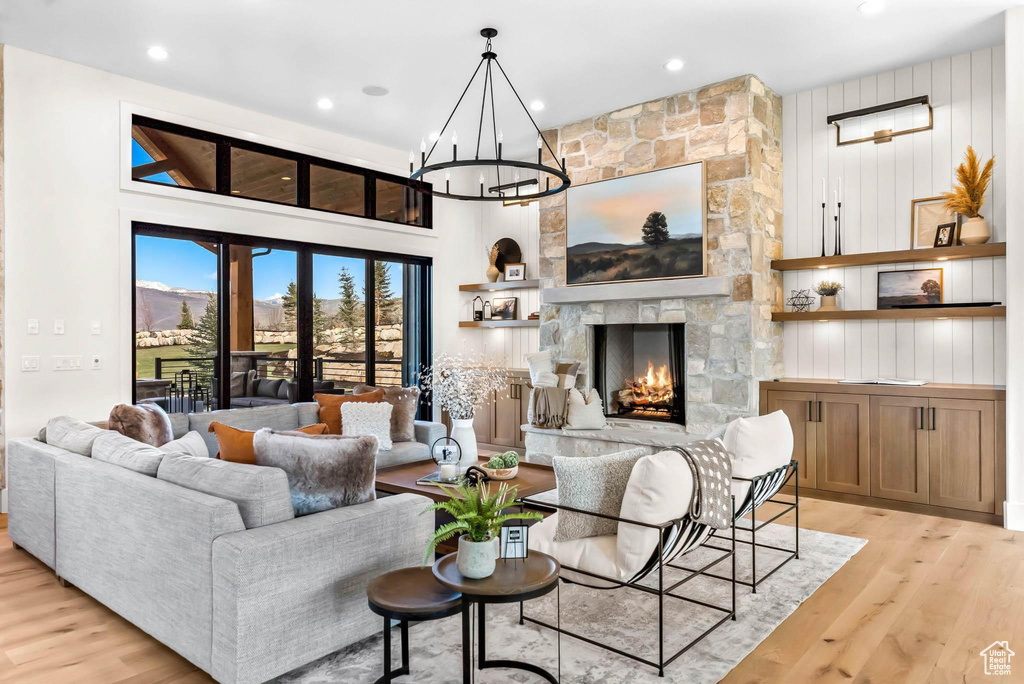Living room with light wood-style floors, a fireplace, a chandelier, and recessed lighting