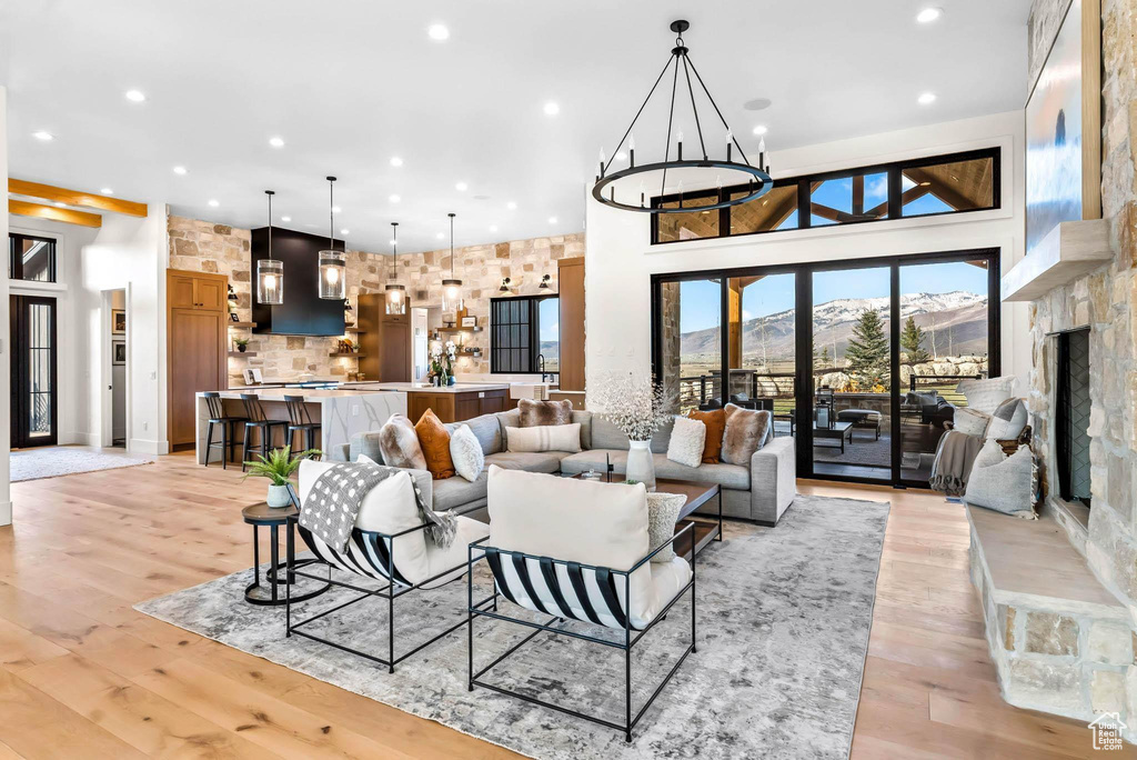 Living area with recessed lighting, a towering ceiling, a chandelier, a mountain view, and light wood-type flooring