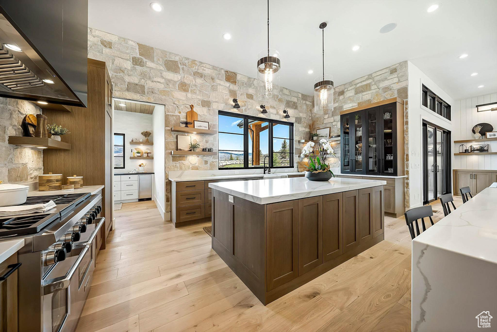 Kitchen with open shelves, wall chimney range hood, range with two ovens, light wood-style flooring, and recessed lighting