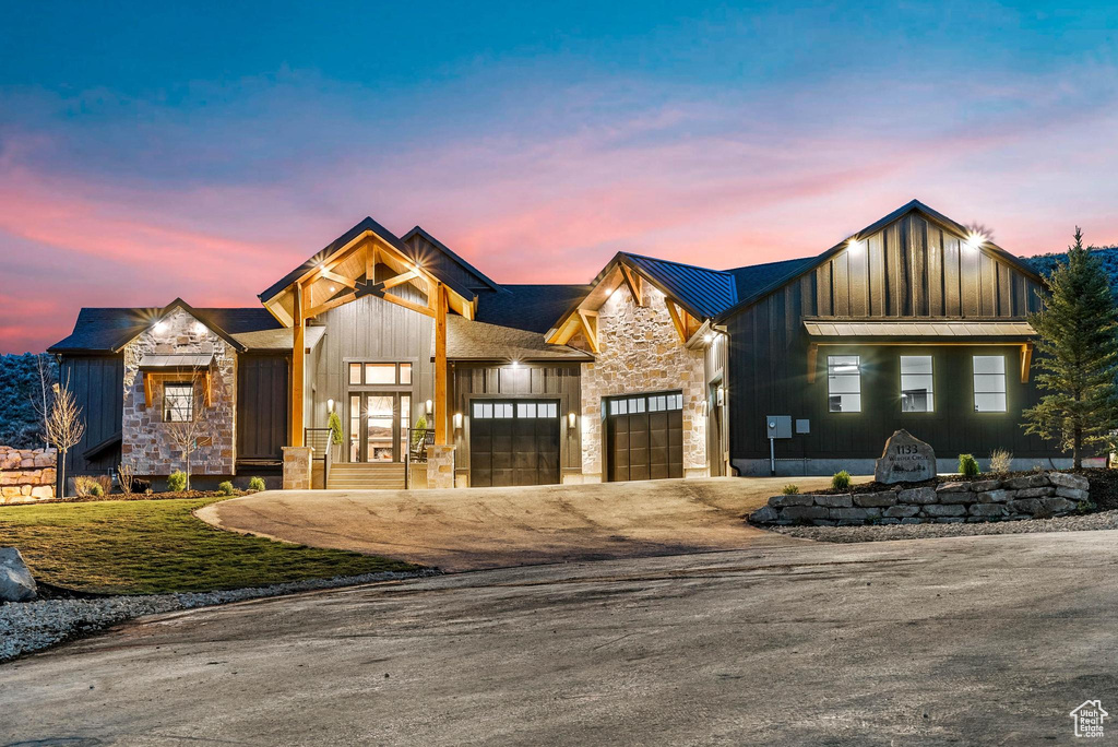 Modern farmhouse featuring board and batten siding, stone siding, an attached garage, and driveway