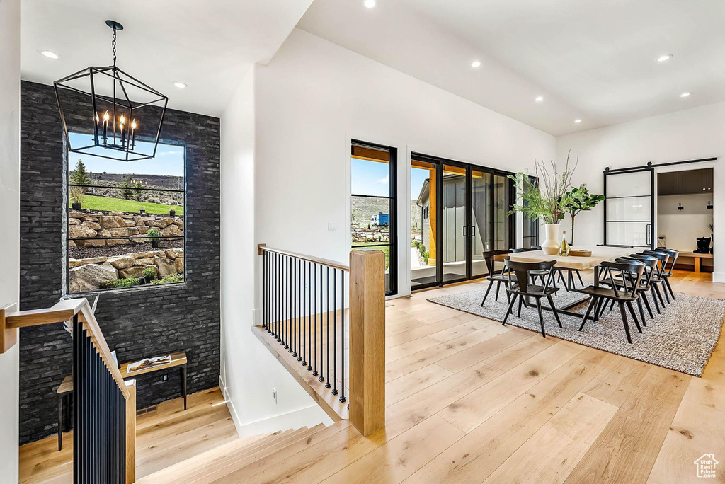 Dining room featuring a chandelier, wood-type flooring, plenty of natural light, a barn door, and recessed lighting