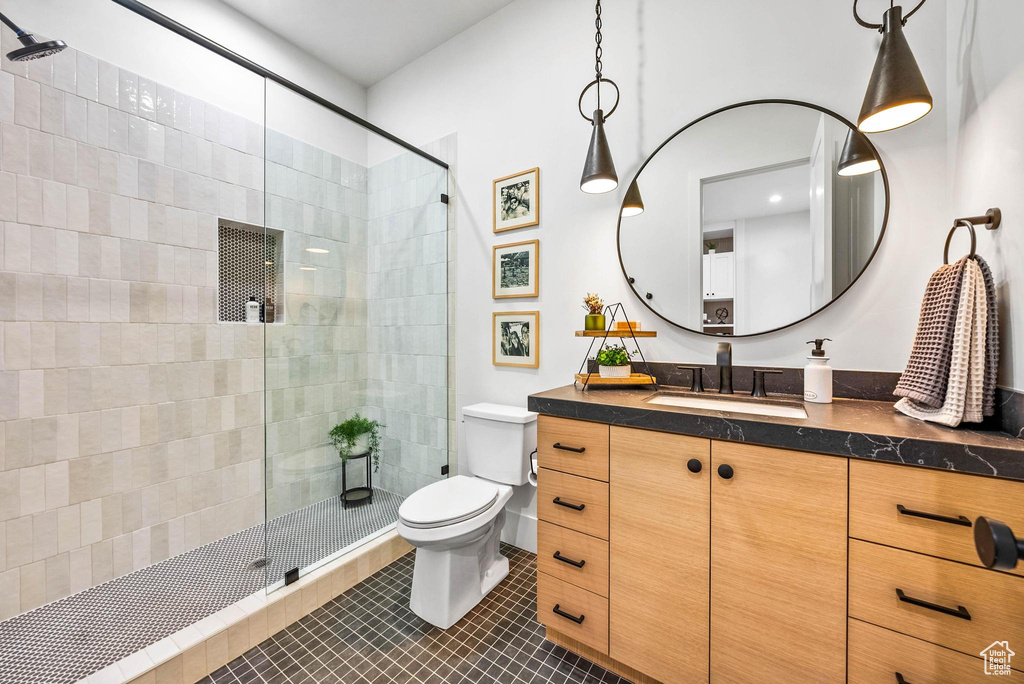 Full bathroom with vanity, tiled shower, and tile patterned flooring