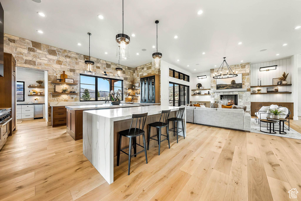 Kitchen featuring a large island, light wood-style floors, light countertops, a kitchen bar, and recessed lighting