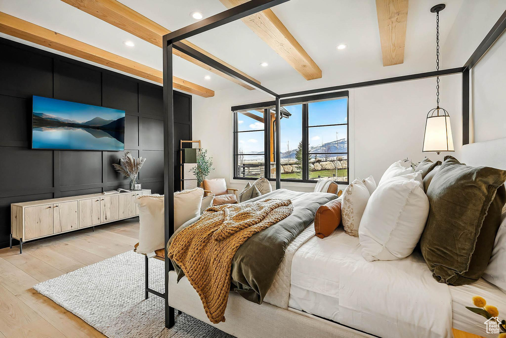 Bedroom featuring light wood-style floors, beamed ceiling, a decorative wall, and recessed lighting