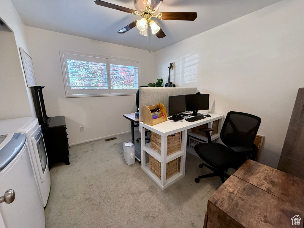 Home office featuring washing machine and clothes dryer, ceiling fan, and light carpet