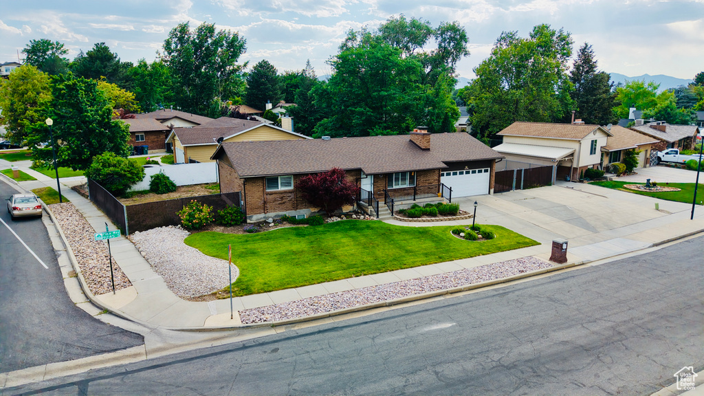 Single story home with an attached garage, a chimney, driveway, a residential view, and brick siding