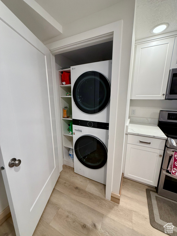Laundry area with estacked washer and dryer and light wood-style flooring