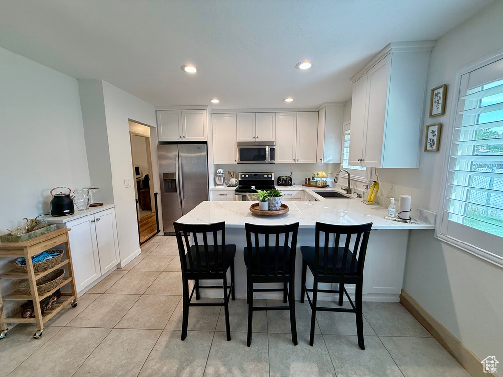 Kitchen featuring stainless steel appliances, a peninsula, healthy amount of natural light, white cabinets, and recessed lighting