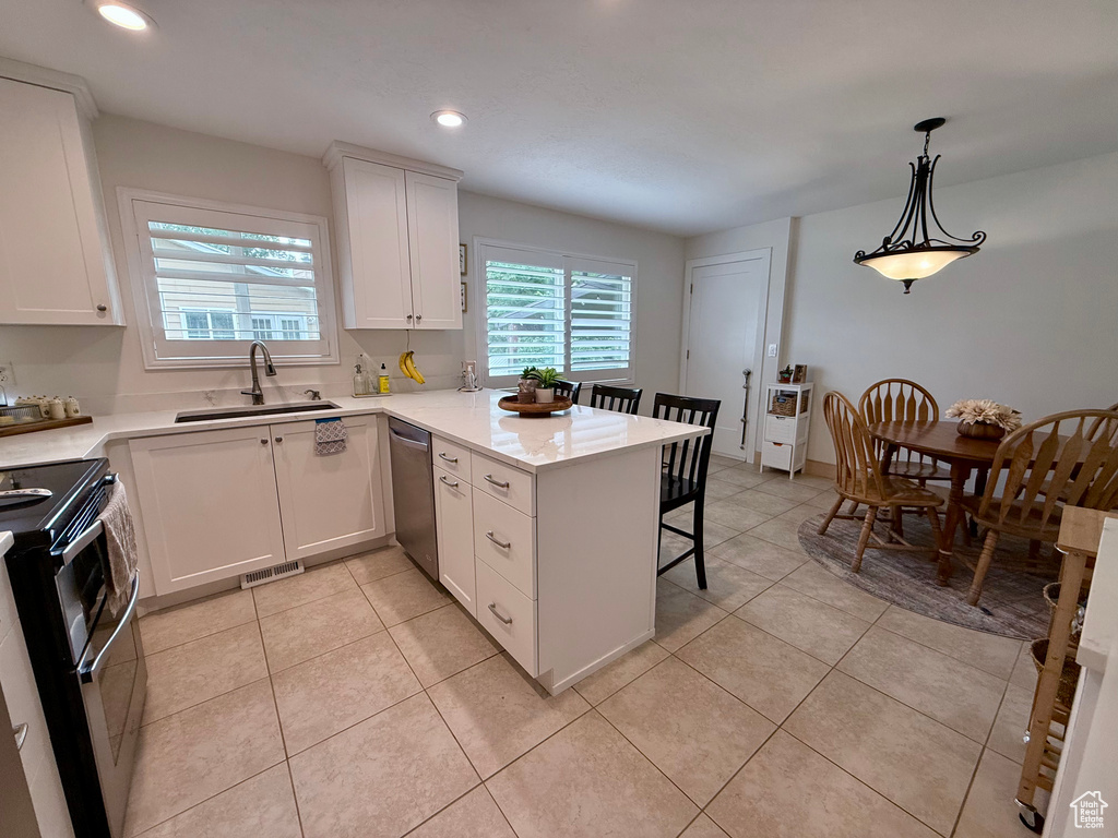 Kitchen featuring stainless steel appliances, white cabinetry, a kitchen bar, a peninsula, and recessed lighting
