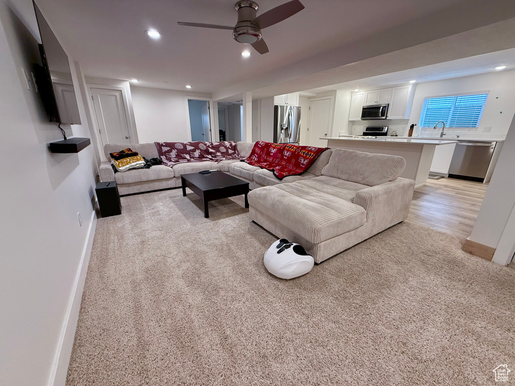 Living area with recessed lighting, light carpet, and a ceiling fan