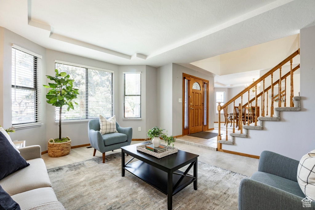Living room with a raised ceiling, baseboards, and stairs