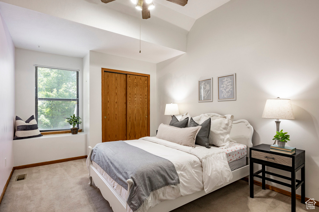 Bedroom with carpet, baseboards, a closet, lofted ceiling, and a ceiling fan
