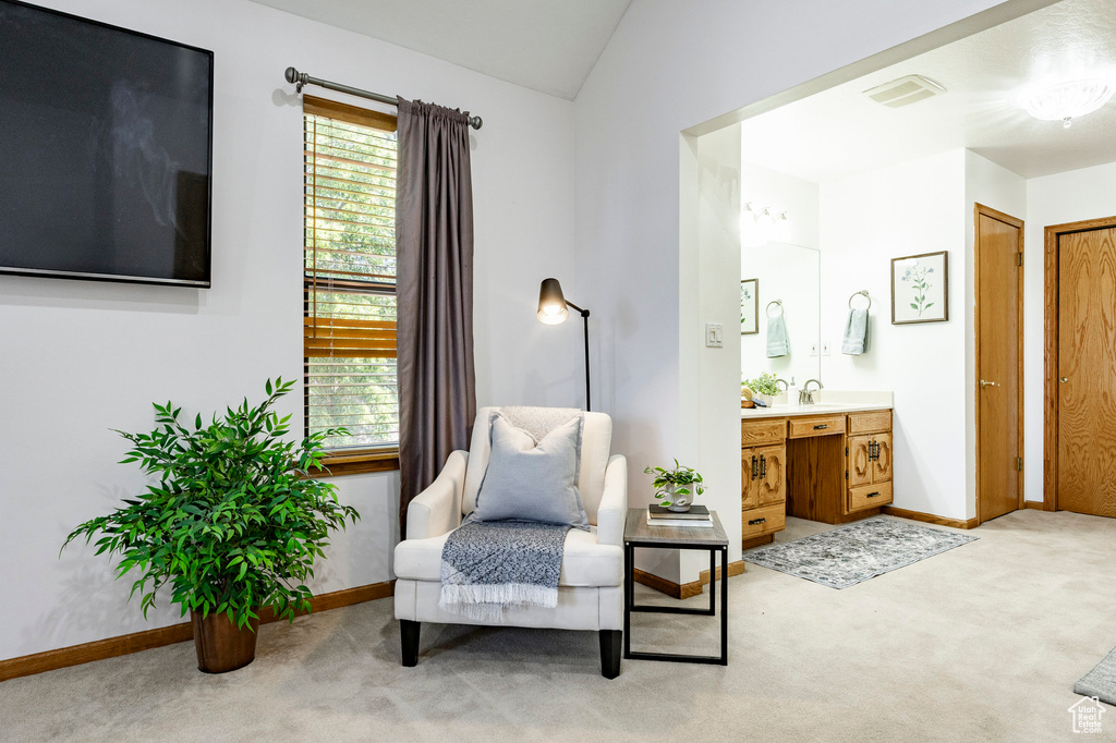 Living area featuring light carpet, baseboards, and lofted ceiling