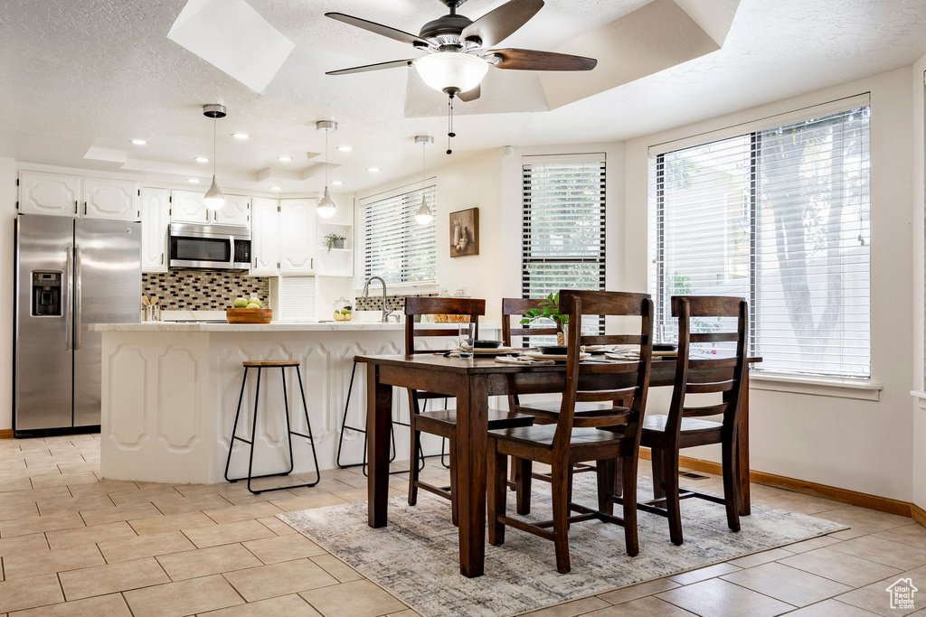 Dining space featuring a tray ceiling, plenty of natural light, a ceiling fan, recessed lighting, and a textured ceiling