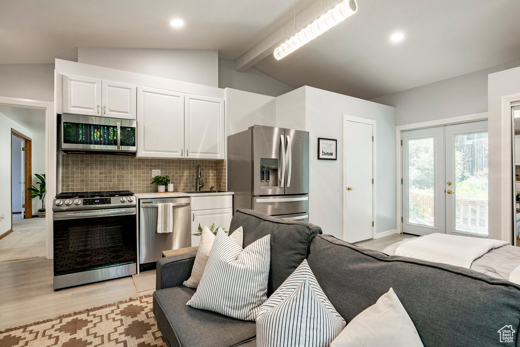 Kitchen featuring stainless steel appliances, backsplash, white cabinetry, french doors, and light wood-style flooring