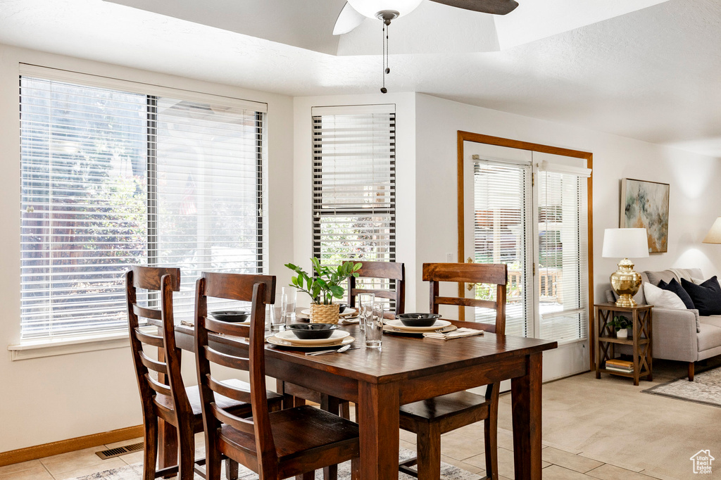 Dining area with plenty of natural light, a ceiling fan, baseboards, and light tile patterned flooring