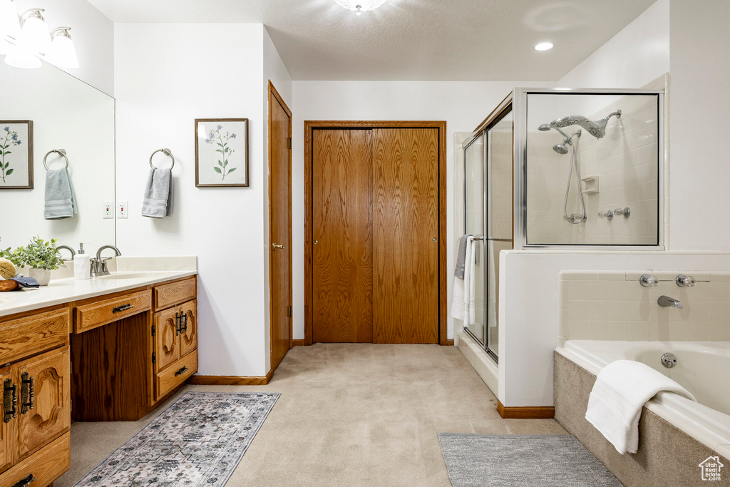 Bathroom with vanity, a shower stall, a bath, and baseboards