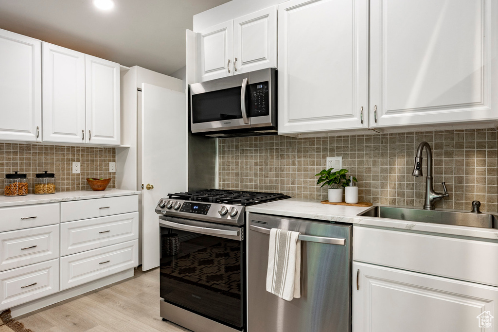 Kitchen featuring stainless steel appliances, a sink, tasteful backsplash, and light countertops