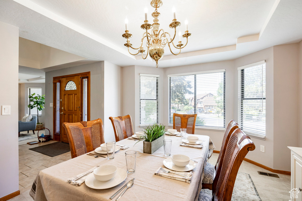 Dining room featuring a tray ceiling, a chandelier, and baseboards