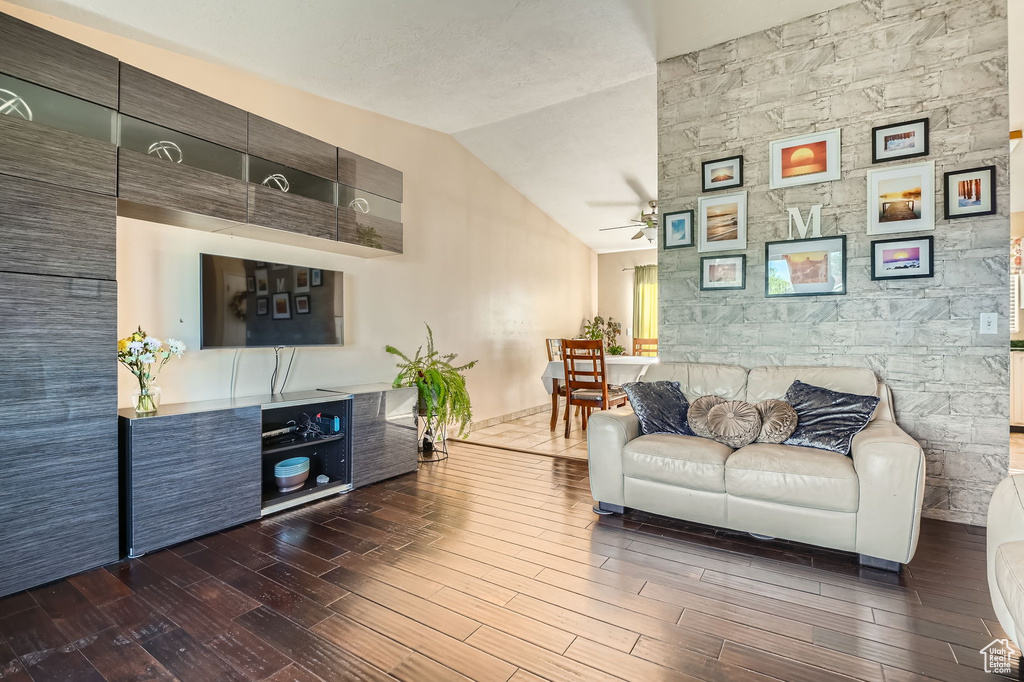 Living room with wood finished floors, a ceiling fan, and vaulted ceiling