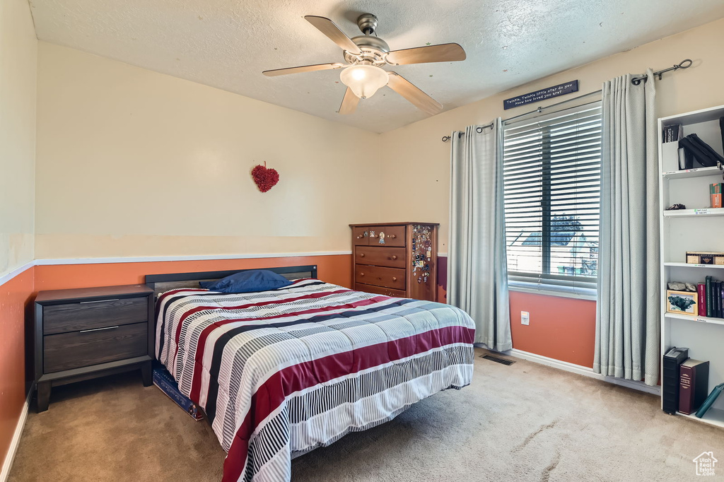 Bedroom featuring carpet flooring, a textured ceiling, and a ceiling fan