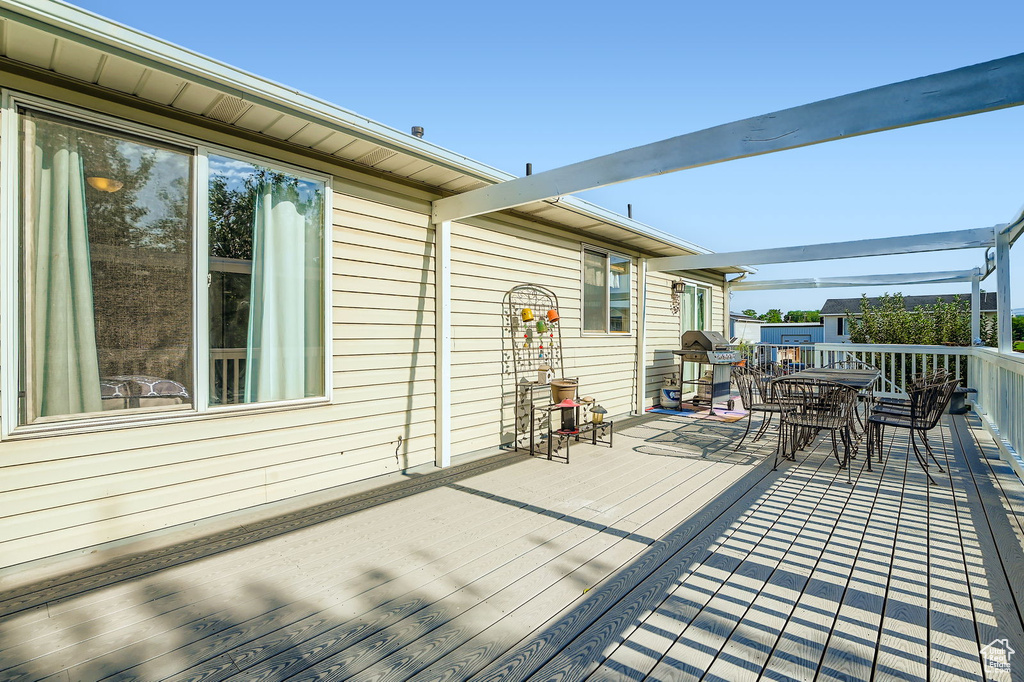 Wooden terrace featuring outdoor dining area and a grill