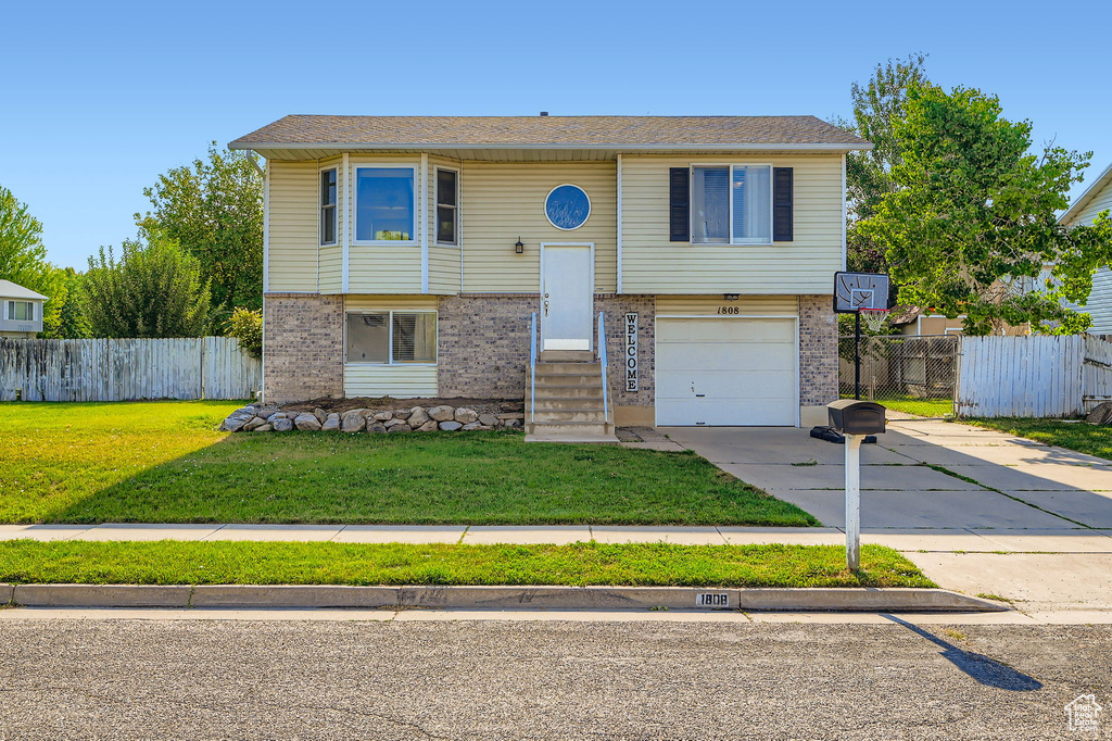 Split foyer home with concrete driveway, brick siding, and an attached garage