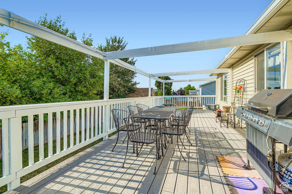 Wooden deck featuring outdoor dining space and a grill