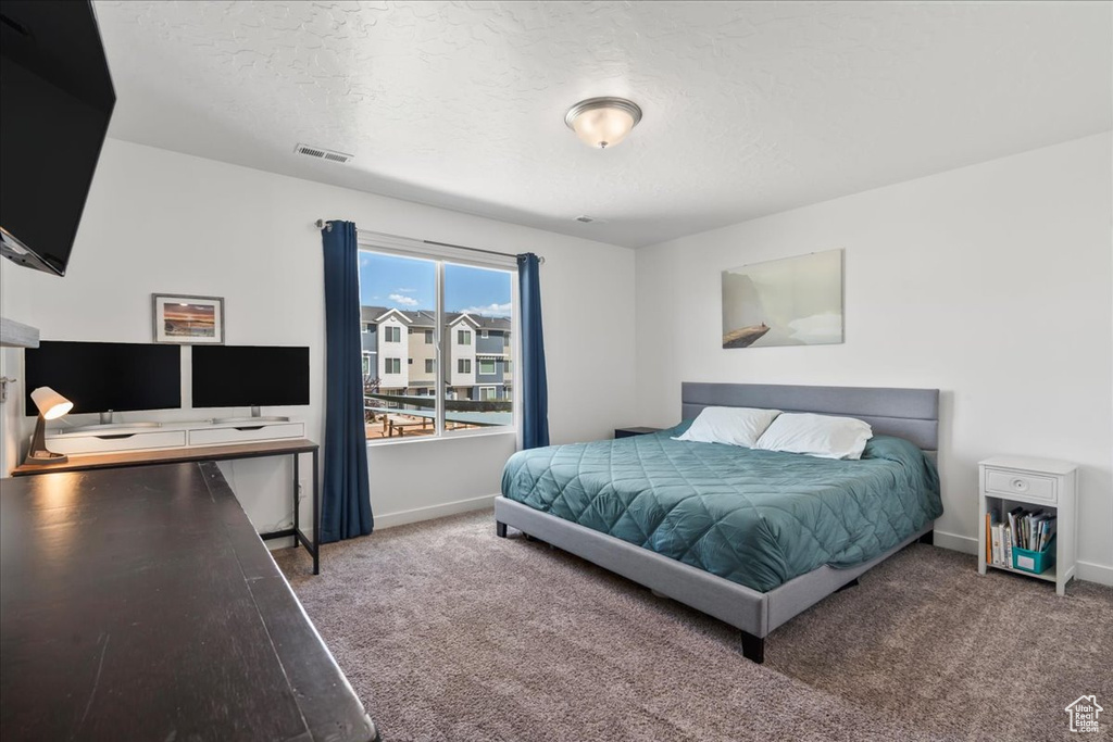 Carpeted bedroom featuring a textured ceiling and a desk