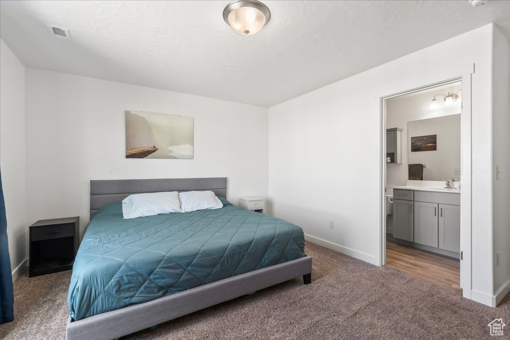 Bedroom featuring carpet flooring, ensuite bath, and a textured ceiling