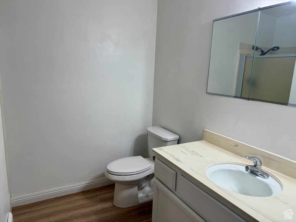 Full bath with vanity, a shower with door, and wood finished floors