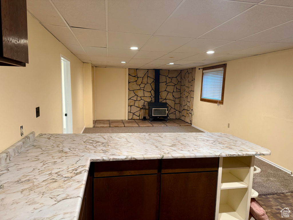 Finished below grade area with a wood stove, a drop ceiling, and recessed lighting