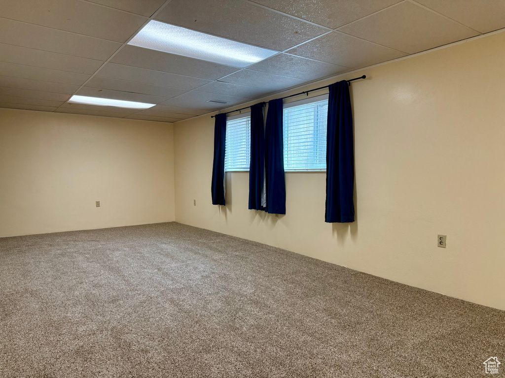 Empty room with carpet and a paneled ceiling