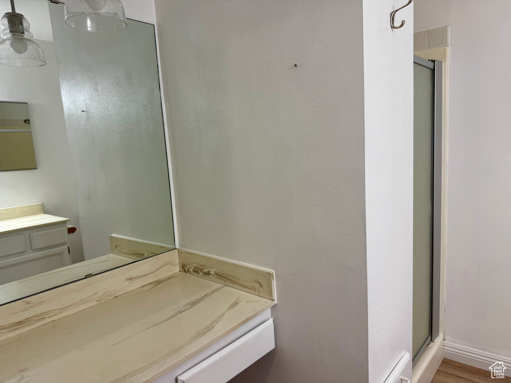 Bathroom featuring a stall shower, vanity, and wood finished floors