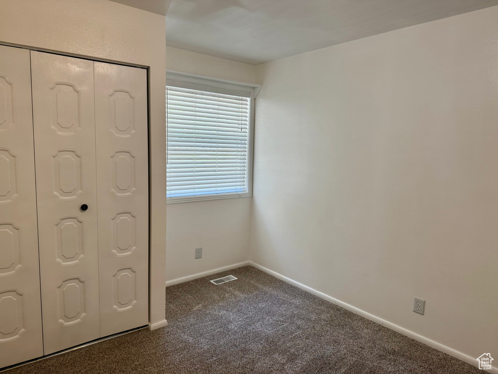 Unfurnished bedroom with dark carpet and a closet
