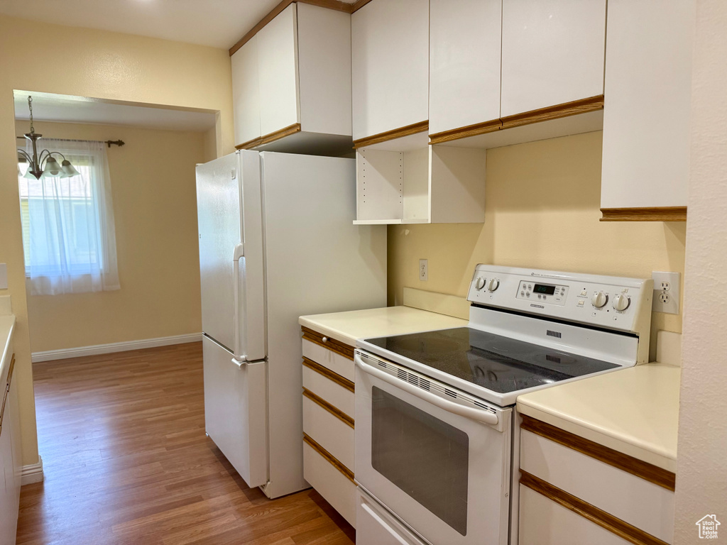 Kitchen featuring white appliances, white cabinets, light wood-style floors, and light countertops