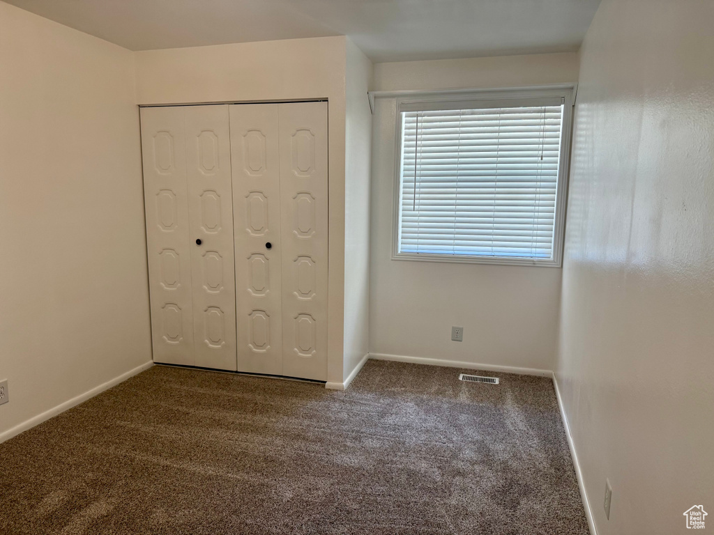 Unfurnished bedroom with carpet and a closet