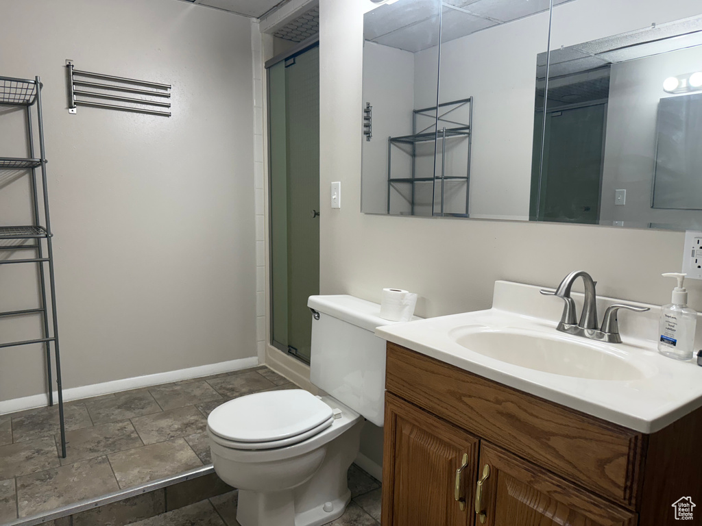 Bathroom with vanity, a shower with shower door, and stone finish flooring